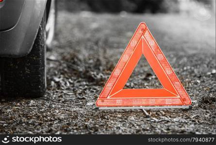 Car transportation. Breakdown of car transporation. Closeup of red warning triangle sign symbol on the forest road.