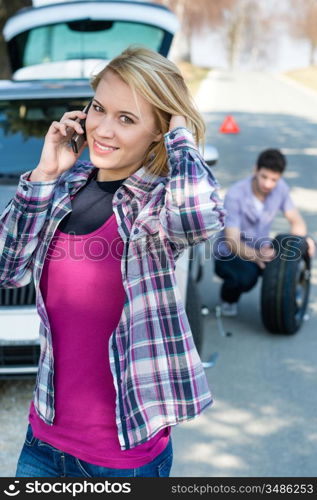 Car trouble woman calling road assistance man change broken wheel