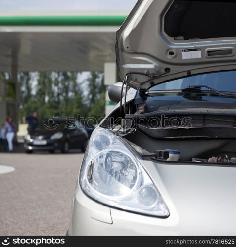 Car with open bonnet at a gas station