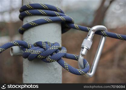 Carabine and climbing rope in knot. Climbing equipment.