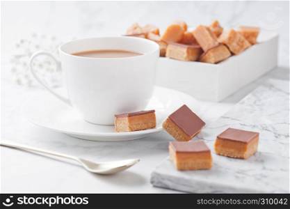 Caramel and biscuit shortcake bites dessert on marble board and coffe cup