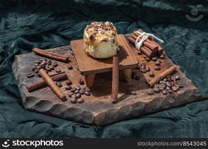 Caramel Pecanbon topped with decadent caramel frosting and pecans served with Cinnamon, Coffee beans on wooden with dark background. Copy space, Selective focus.