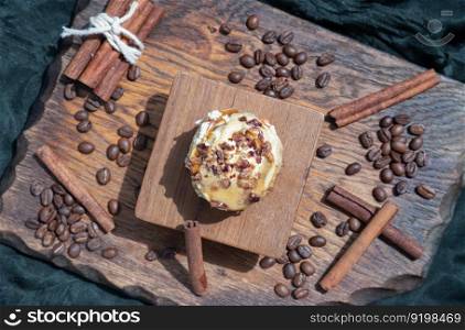 Caramel Pecanbon topped with decadent caramel frosting and pecans served with Cinnamon, Coffee beans on wooden with dark background. Top view, Selective focus.