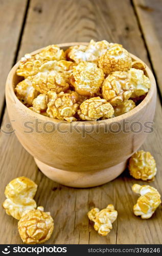 Caramel popcorn in a wooden bowl on a wooden boards background