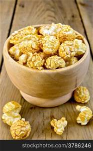Caramel popcorn in a wooden bowl on a wooden boards background