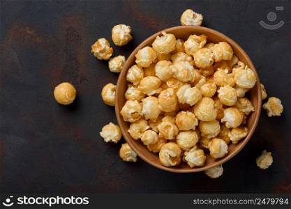 Caramel popcorn in bowl on dark table background