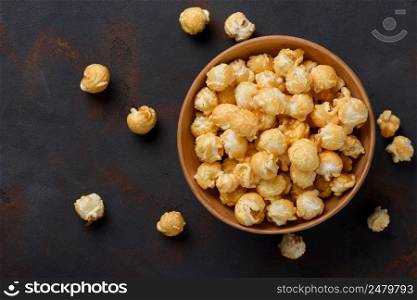 Caramel popcorn in bowl on dark table background top view
