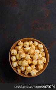 Caramel popcorn in bowl vertical on dark table with copy space