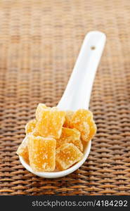 Caramelized ginger candy pieces on white spoon