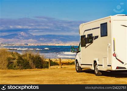 Caravan on mediterranean coast, Alicante city in the distance, Costa Blanca Spain. Wild c&ing on beach. Holidays and traveling in motor home.. Rv motor home c&ing on beach