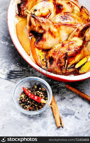 Carcasses of quail roasted with orange in baking dish. Delicious fried quail