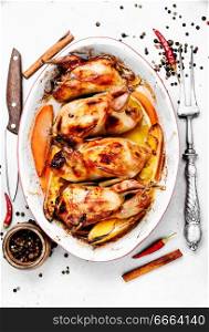 Carcasses of quail roasted with orange sauce in baking dish. Baked whole quail