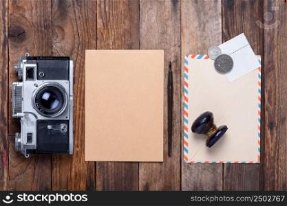 Card with envelope, stamps and retro camera on old wooden table still life