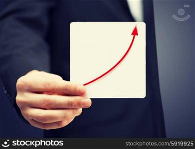card with increasing graph on it. man in suit holding card with increasing graph on it