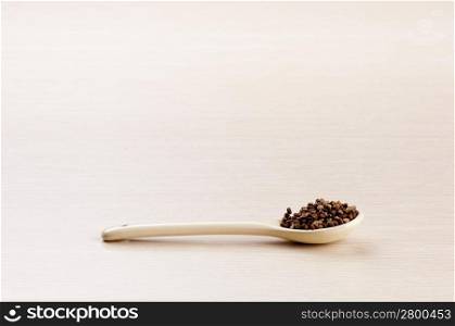 Cardamom Seeds in a spoon over a blured wooden background with copy space