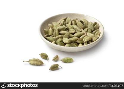 Cardamom seeds on a dish on white background