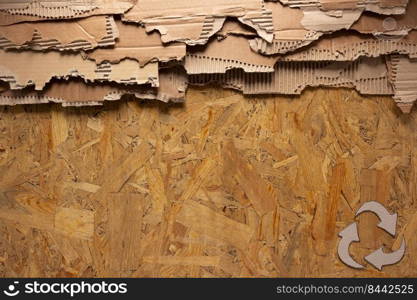Cardboard torn edge and recycle symbol at chipboard plywood background texture. Brown ripped paper