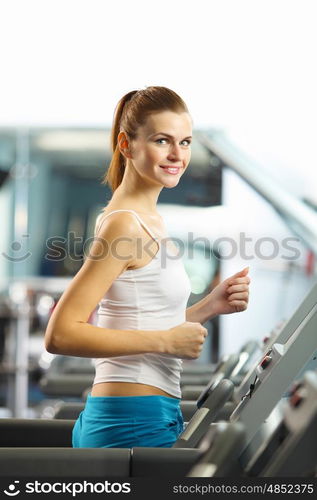 Cardio workout. Image of fitness girl running on treadmill