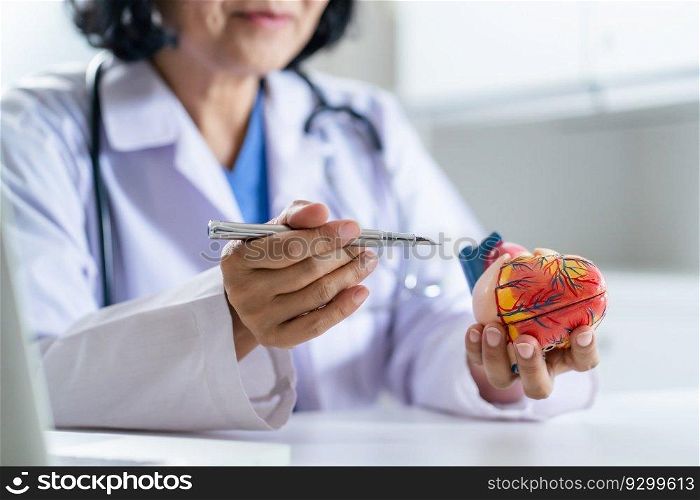 Cardiologist supports the heart senior asian woman doctor wearing glasses and uniform. portrait of mature old asian woman medic professional.
