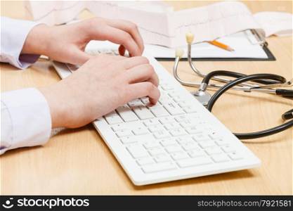 cardiologist works on white PC keyboard close up