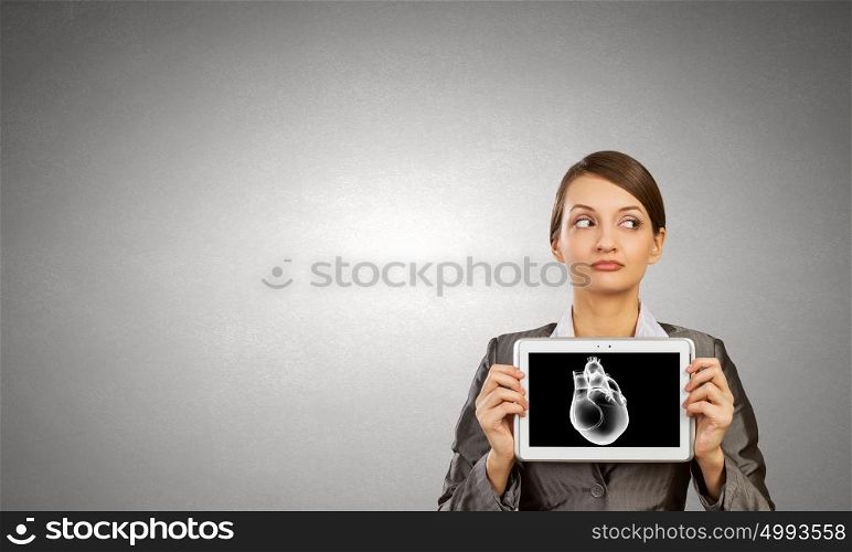 Cardiology concept. Young businesswoman showing tablet pc against heart