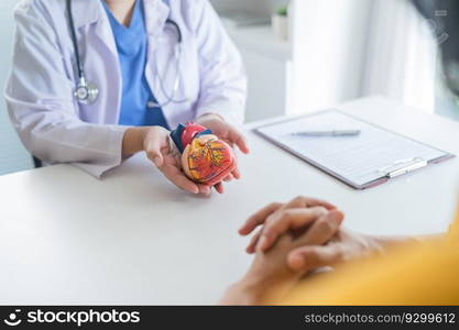 Cardiology Consultation treatment of heart disease. Doctor cardiologist while consultation showing anatomical model of human heart with aged patient talking about heart diseases