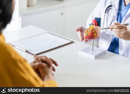 Cardiology Consultation treatment of heart disease. Doctor cardiologist while consultation showing anatomical model of human heart with aged patient talking about heart diseases