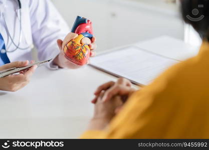 Cardiology Consultation treatment of heart disease. Doctor cardiologist while consultation showing anatomical model of human heart with aged patient talking about heart diseases