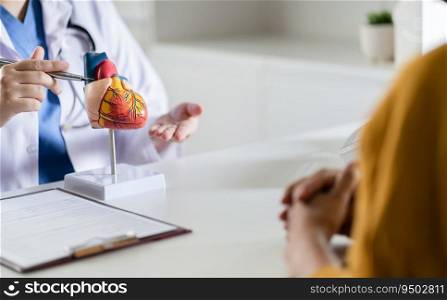 Cardiology Consultation treatment of heart disease. Doctor cardiologist while consultation showing anatomical model of human heart with aged patient talking about heart diseases