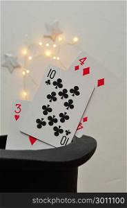 Cards in a magicians hat with silver stars and out of focus lights