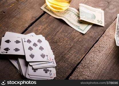 cards, whisky and money lying on a wooden table