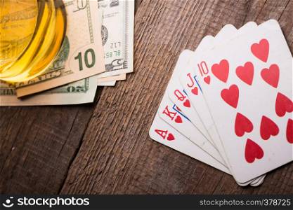 cards, whisky and money lying on a wooden table