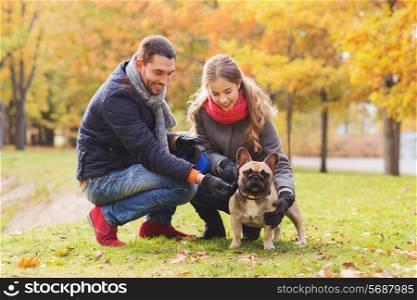 care, animals, family, season and people concept - smiling couple with dog in autumn park