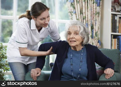 Care Worker Helping Senior Woman To Get Up Out Of Chair