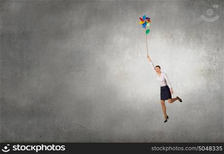 Carefree and happy. Beautiful young caucasian businesswoman flying on windmill