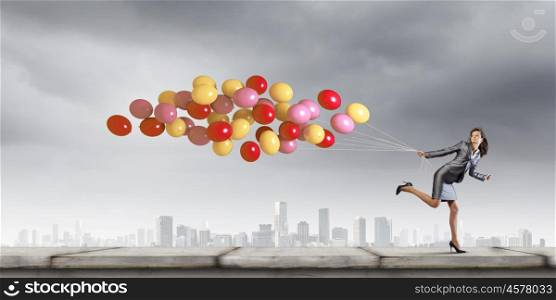 Carefree businesswoman. Young businesswoman with bunch of balloons running in a hurry
