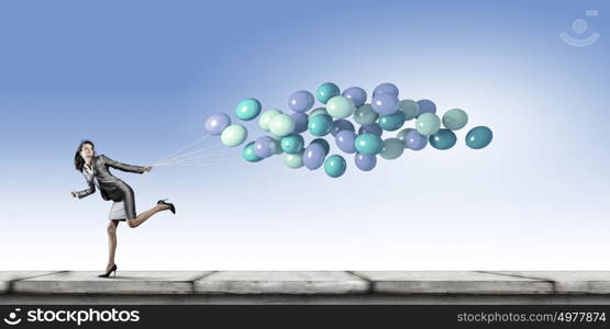 Carefree businesswoman. Young businesswoman with bunch of balloons running in a hurry