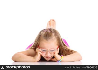 Carefree days of childhood. Cute little girl lying on floor with feet up doing fun studio shot isolated on white background