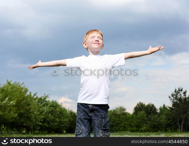 carefree litlle boy outdoors embracing skies on lawn