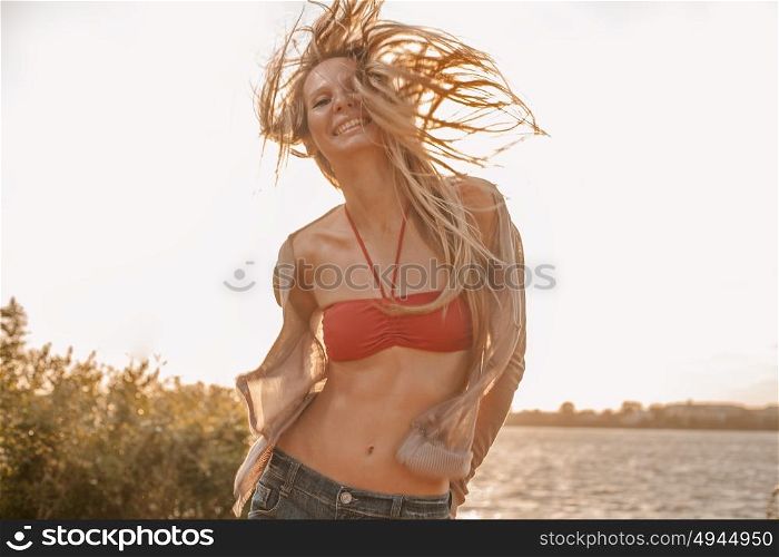 Carefree woman dancing in the sunset light on the beach. Vacation happy living concept retro color shot copyspace. Carefree woman dancing in the sunset light on the beach. Vacation happy living concept retro color shot with copyspace.