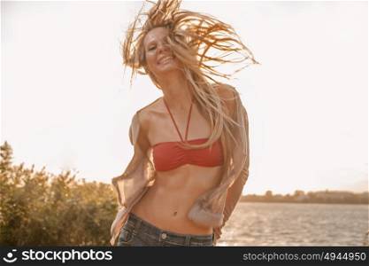 Carefree woman dancing in the sunset light on the beach. Vacation happy living concept retro color shot copyspace. Carefree woman dancing in the sunset light on the beach. Vacation happy living concept retro color shot with copyspace.
