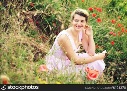 carefree woman sitting in a green field enjoying the summer sunlight