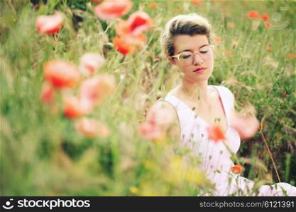 carefree woman sitting in a green field enjoying the summer sunlight