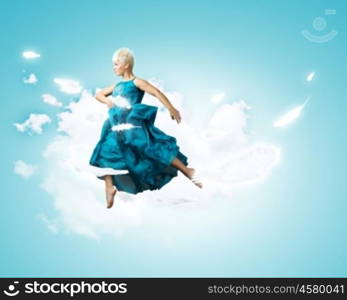 Carefree woman. Young attractive woman in blue dress jumping high