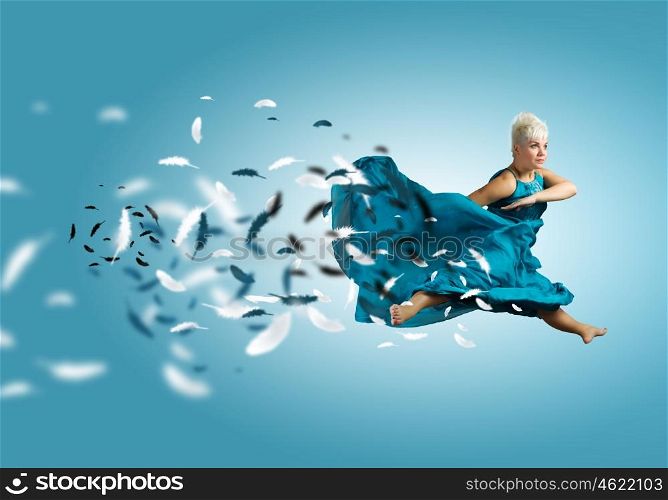 Carefree woman. Young attractive woman in blue dress jumping high