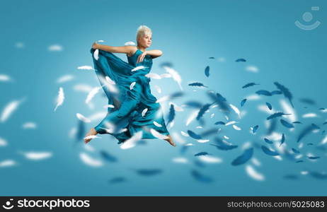 Carefree woman. Young attractive woman in blue dress jumping high