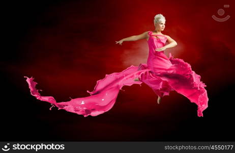 Carefree woman. Young attractive woman in pink dress jumping high