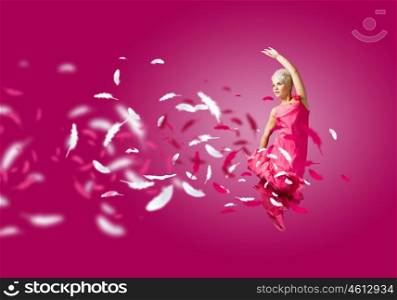 Carefree woman. Young attractive woman in pink dress jumping high