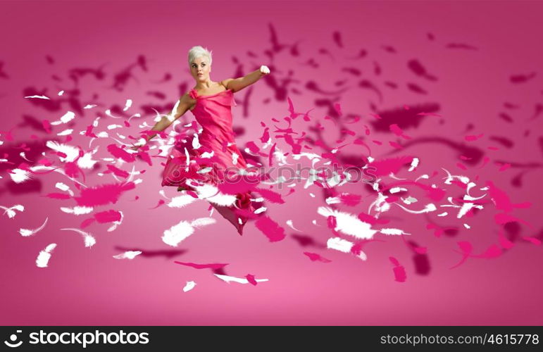 Carefree woman. Young attractive woman in pink dress jumping high