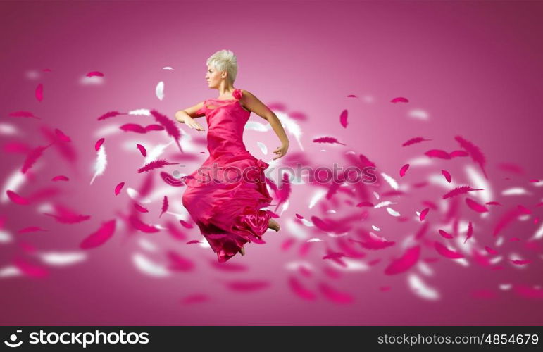 Carefree woman. Young attractive woman in pink dress jumping high